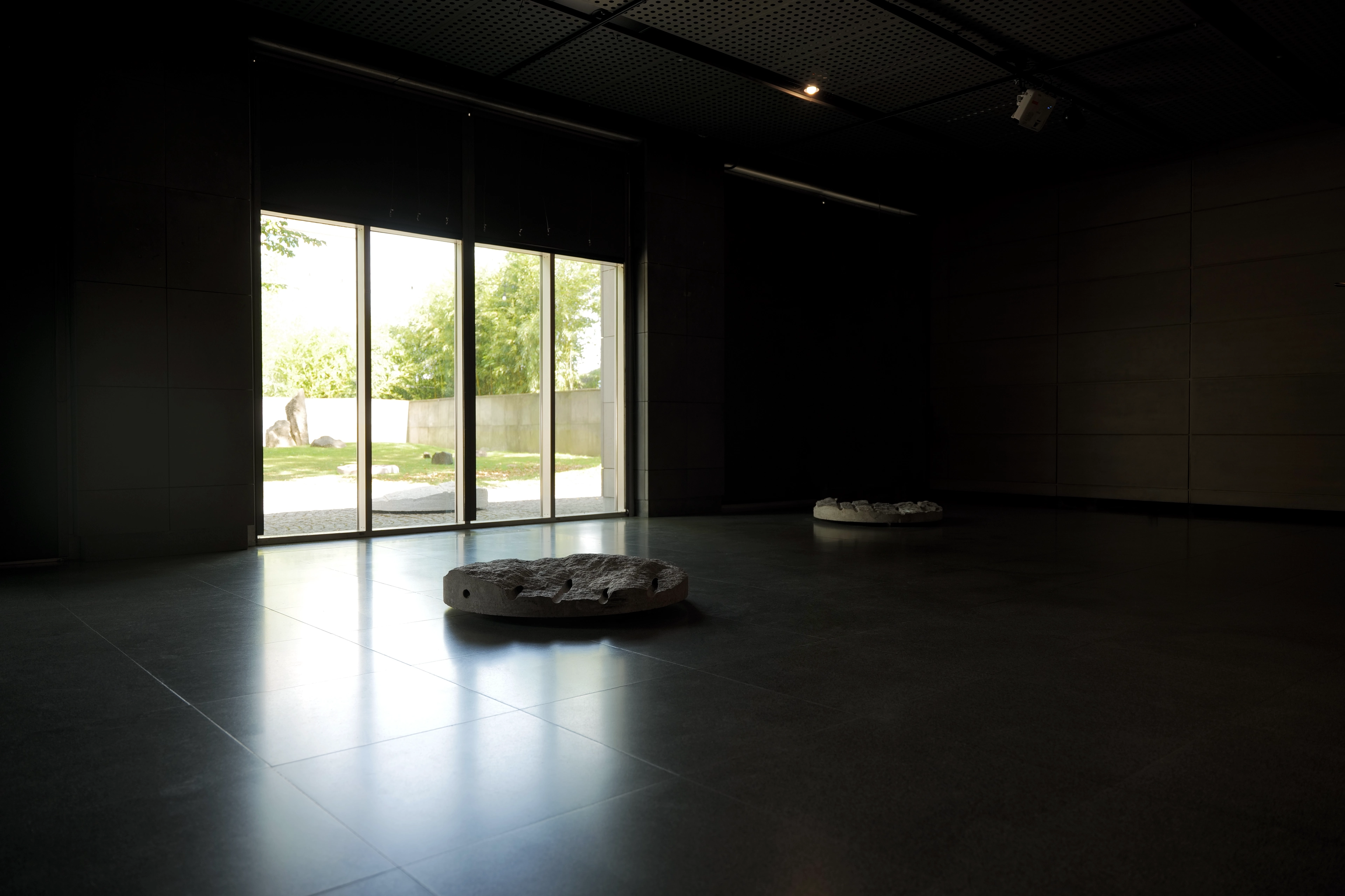 “Primes" sculpture installation by Ewa Wes Wesołowska, exhibited at the Manggha Museum in Cracow, featuring granite objects with projected Wilson cloud chamber recordings