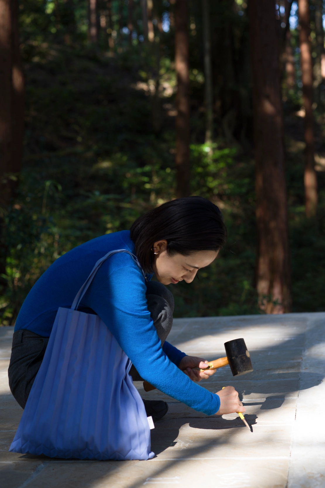 A woman carving into the stone surface of Liminality, a participatory public artwork by Ewa Wes (Wesołowska) in Kamiyama, Japan.