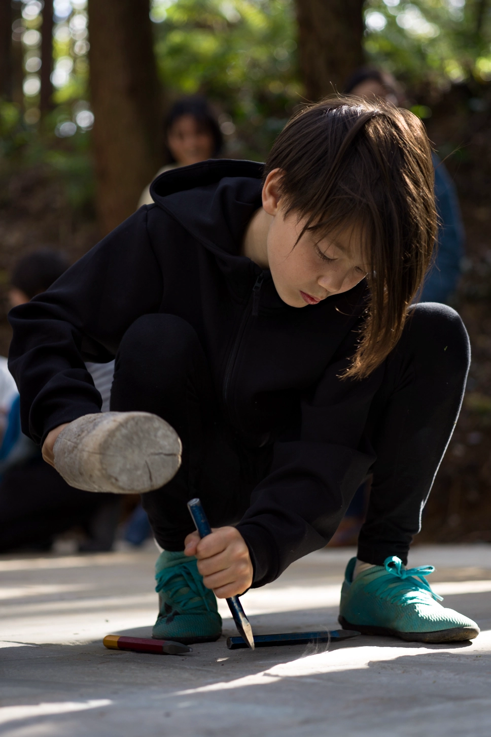 This image captures a boy carving into the stone floor of Liminality, an interactive public artwork by Ewa Wes (Wesołowska) in Kamiyama, Japan.