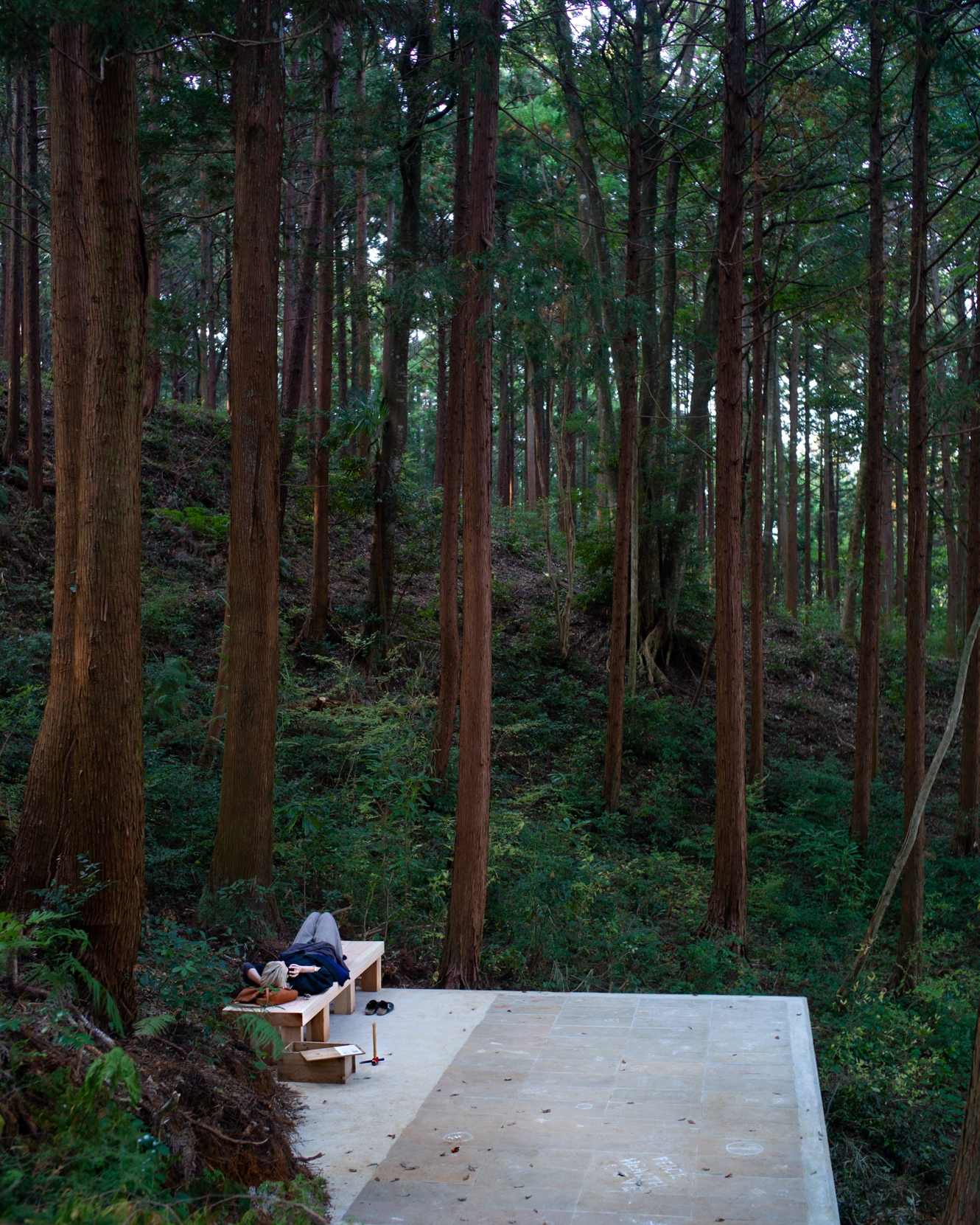A person lying on their back on a bench at Liminality, an interactive public artwork by Ewa Wes (Wesołowska) in Kamiyama, Japan, offering a place for relaxation and contemplation.