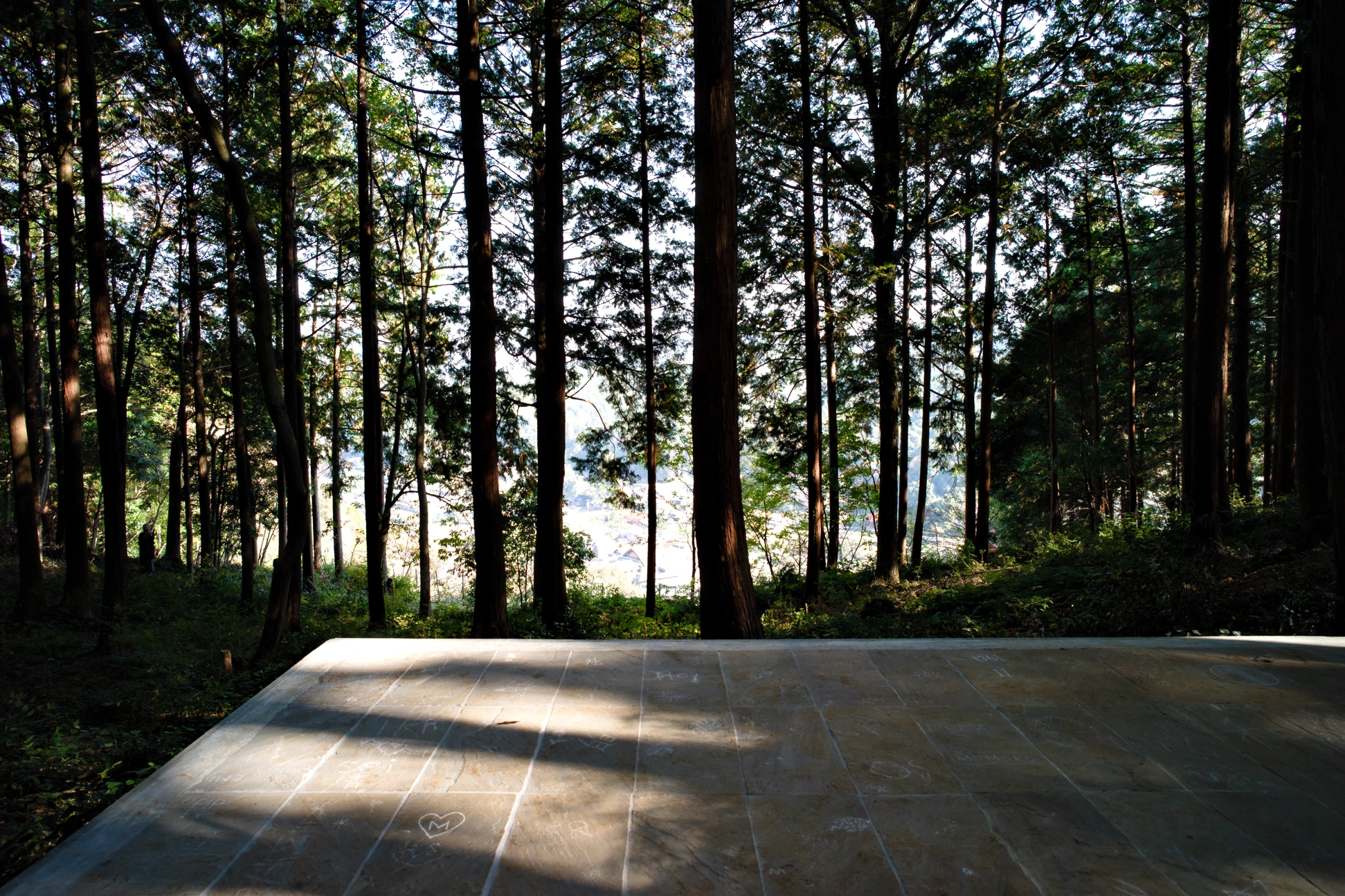 The stone floor of Liminality, a public artwork by Ewa Wes (Wesołowska), with carved traces left by visitors, set in the Kamiyama forest at Oawa Mountain overlooking the town.